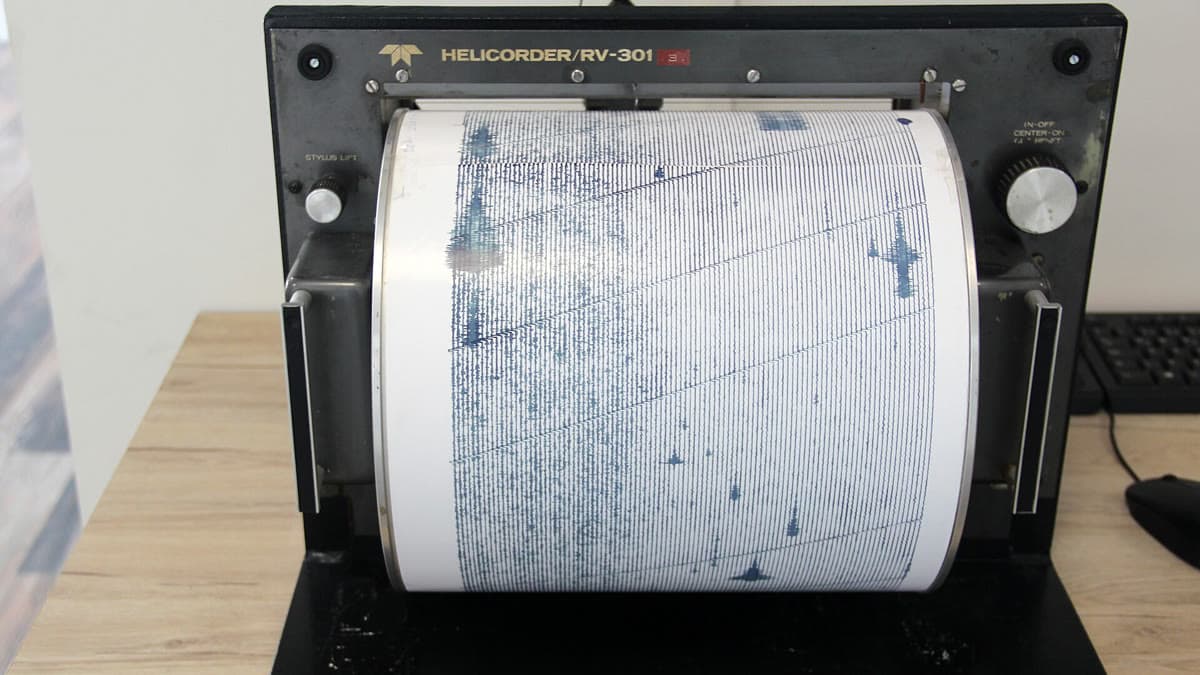 Deprem dalgalarını kaydeden bir sismograf (helikorder) cihazı — temsili görsel