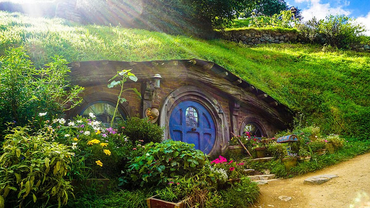 Yeni Zelanda'daki Hobbiton Film Seti'nde çiçeklerle çevrili yuvarlak bir hobbit kapısı