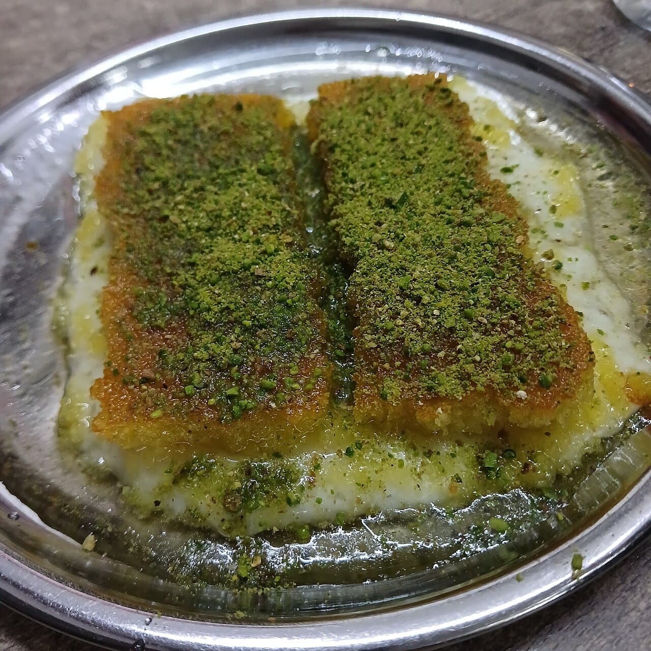 Antep fıstığı serpilmiş, tepside servis edilen künefe yakın çekim