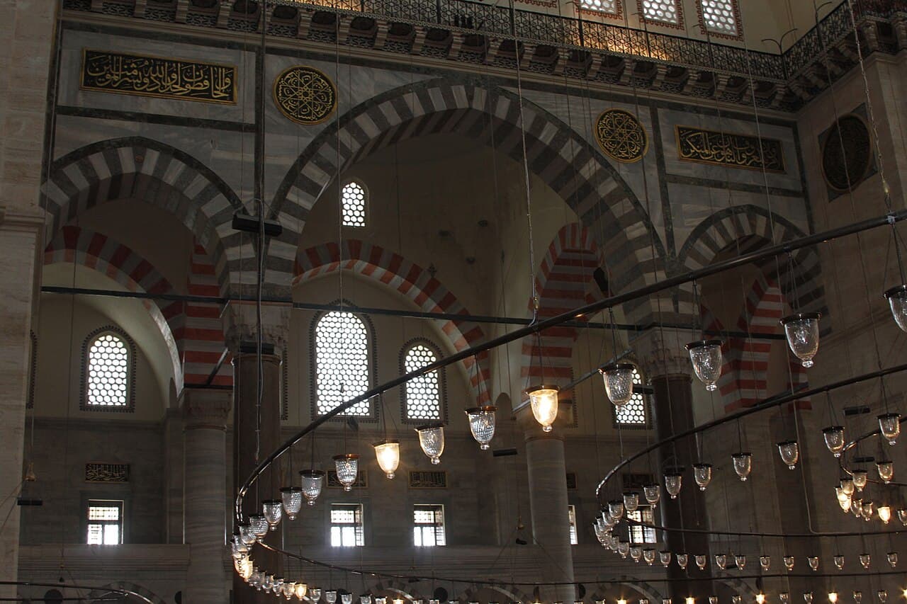 Süleymaniye Camii'nin iç mekânı — kemerler, hat yazıları ve kandil düzeni